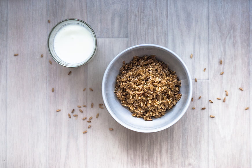 Bowl of Brown Rice and Glass of Milk on Light Wood Table