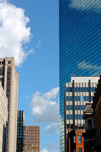 Modern Glass Skyscraper Reflecting Blue Sky and Clouds