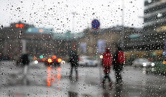 Raindrops on window glass with blurred city street background