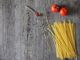 Uncooked spaghetti, tomatoes, and spices on rustic wooden table