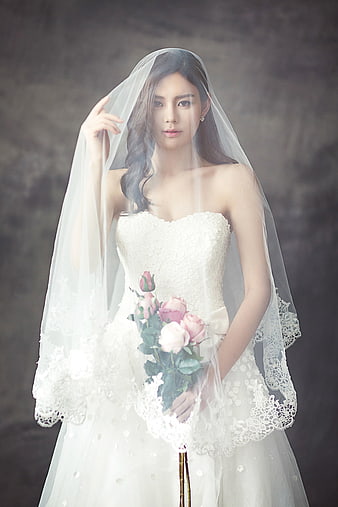 Asian bride in white wedding dress holding pink roses