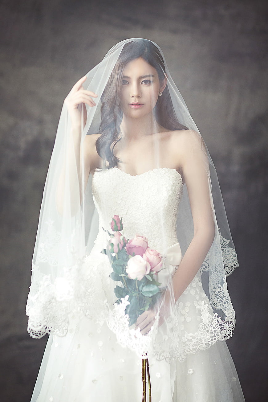 Asian bride in white wedding dress holding pink roses
