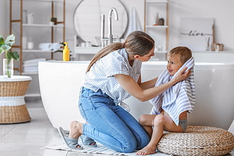 Happy Mother Drying Child with Towel in Modern Bathroom