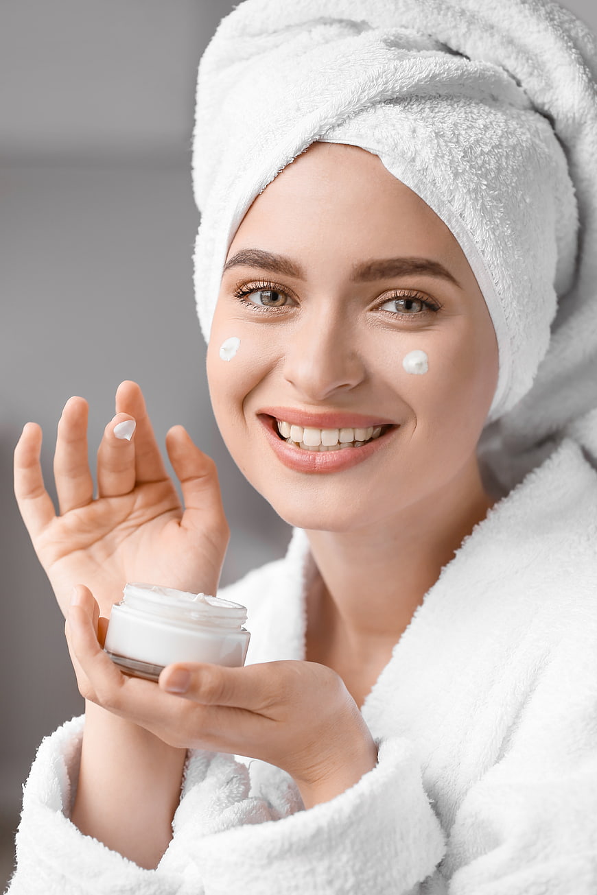 Happy Woman Applying Face Cream with Towel on Head