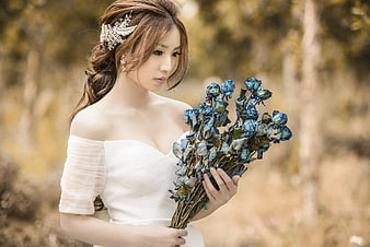 Bride holding blue dried roses in autumn forest