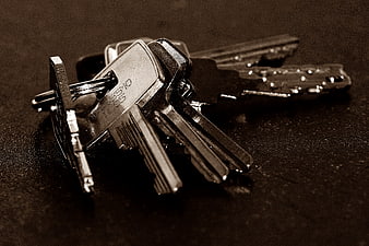Sepia toned close-up of metal keys on a dark textured surface