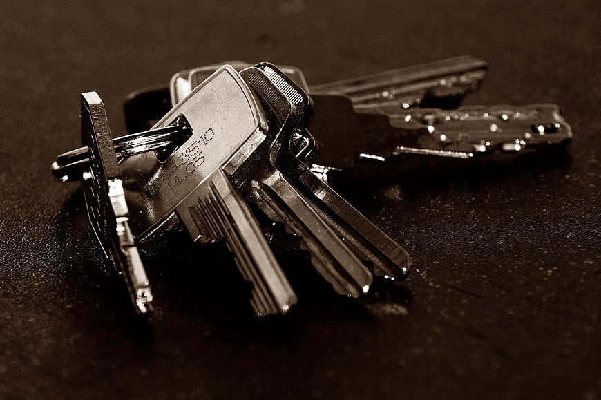 Sepia toned close-up of metal keys on a dark textured surface