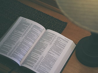 Open Bible on Wooden Table with Lamp