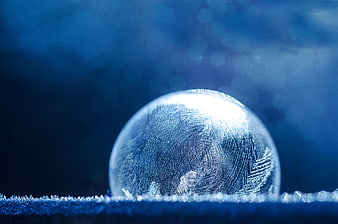 Frozen Soap Bubble with Intricate Ice Crystals on Blue Background