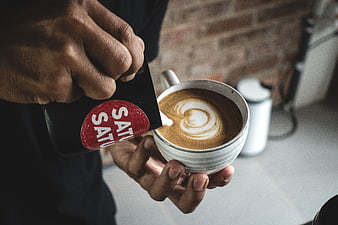 Barista pouring latte art into a coffee cup