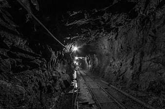 Dark underground mine tunnel with railway tracks and lights