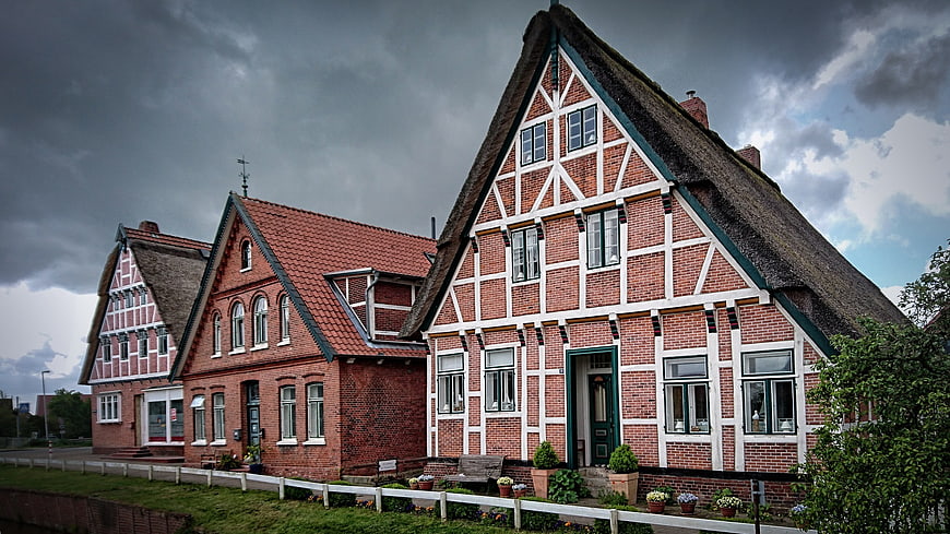 Traditional Half-Timbered Houses with Thatched Roof Under Stormy Sky