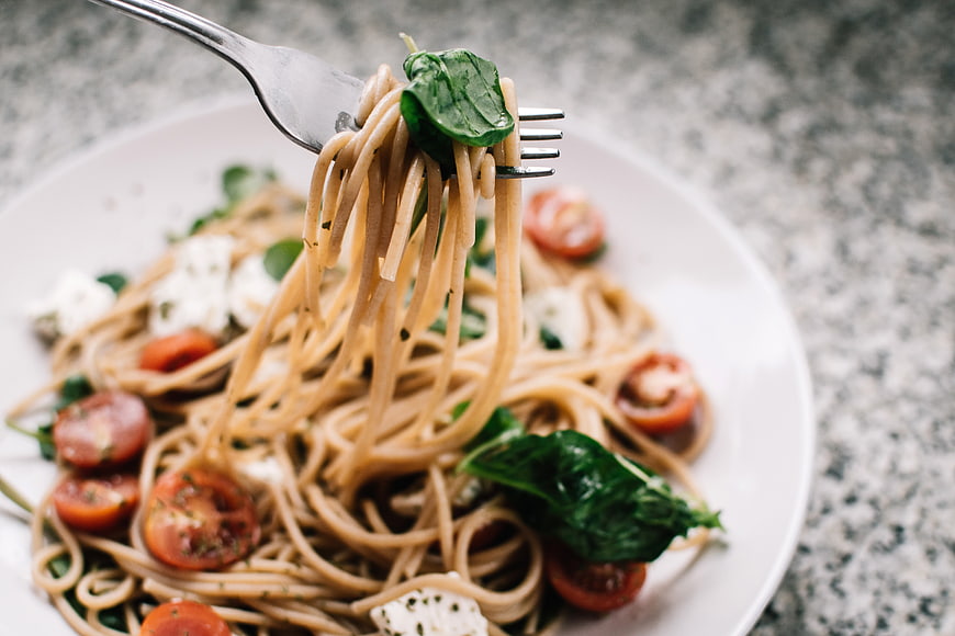 Fork twirling spaghetti with cherry tomatoes and basil