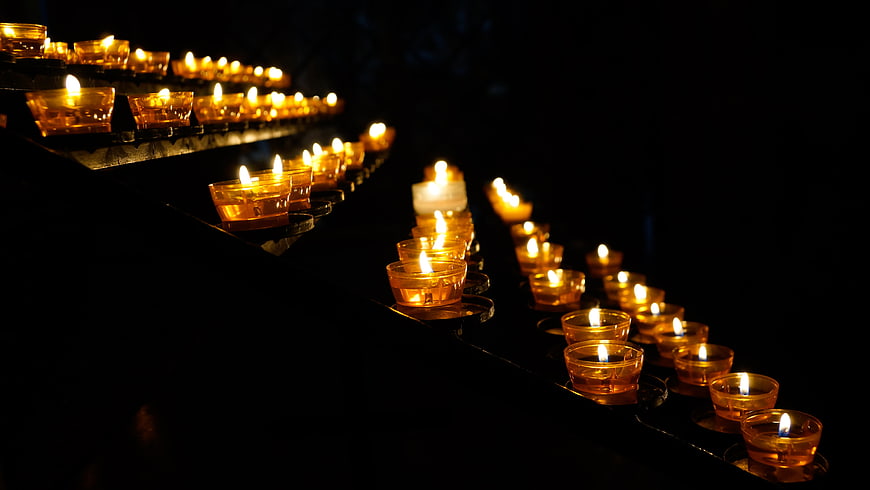 Rows of glowing tea light candles in a dark church interior
