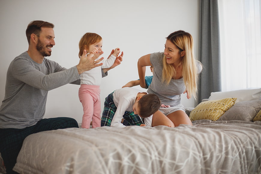 Happy family playing together on bed in bedroom