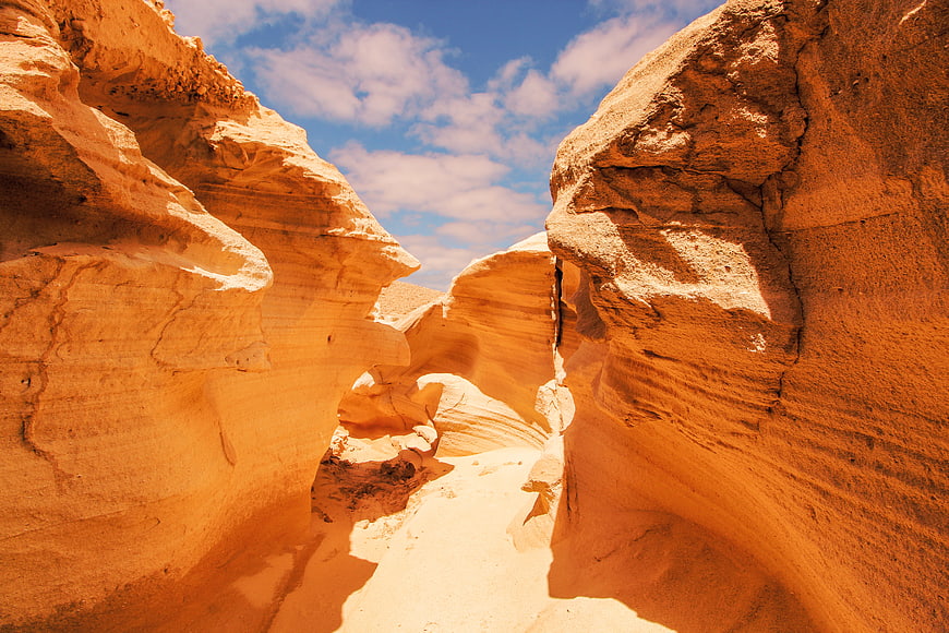 Sunlit sandstone canyon with blue sky and clouds