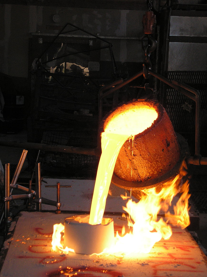 Molten metal pouring from crucible in industrial foundry