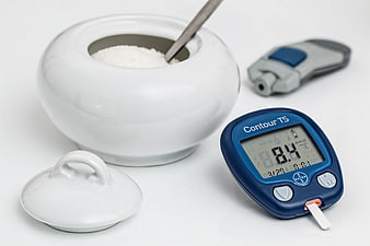 Blood Glucose Meter and Sugar Bowl on White Background