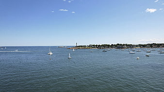 Wide aerial view of sailboats and motorboats in a calm blue harbor