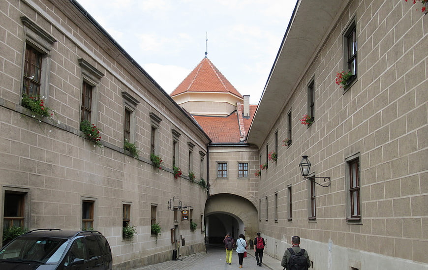 Historic stone courtyard with red-tiled tower and tourists