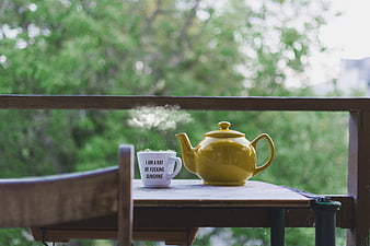 Yellow Teapot and Mugs on Wooden Table with Steam