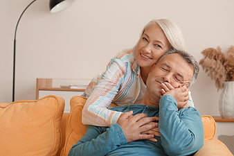Happy Senior Couple Relaxing on Orange Sofa at Home