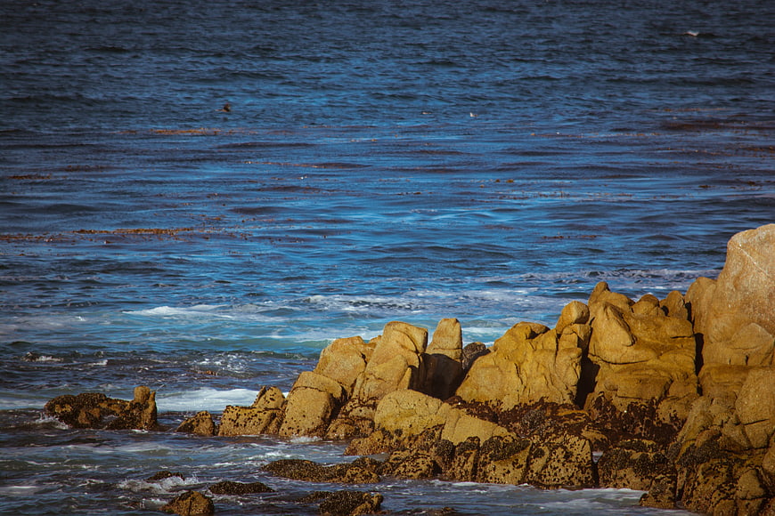 Golden coastal rocks meeting deep blue ocean waves