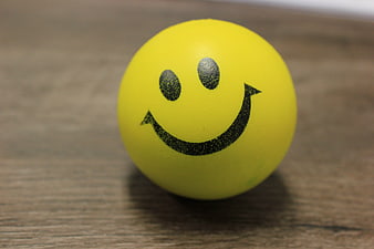 Yellow smiley face ball on wooden surface