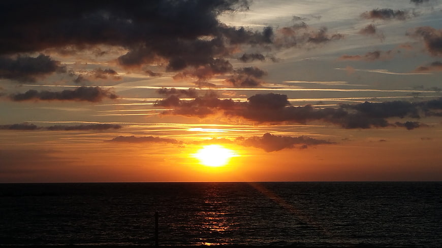 Dramatic sunset over ocean with clouds and sun reflection
