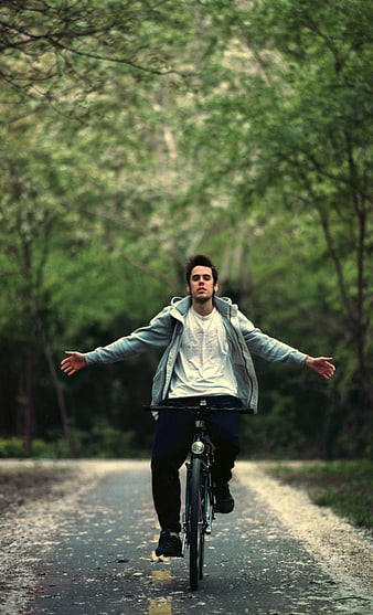 Young Man Riding Bicycle No Hands on Forest Road