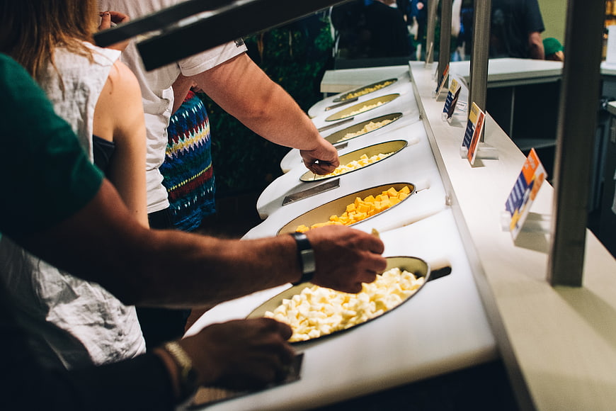 Hands selecting cheese at a deli counter display