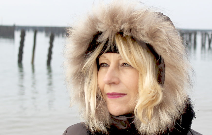Portrait of mature woman in fur hat by water