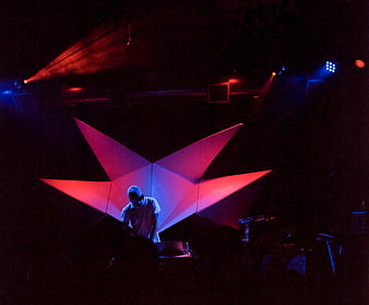 DJ performing on stage with geometric star backdrop and neon lighting