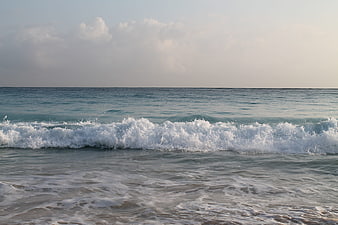 Ocean Wave Breaking on Sandy Beach at Sunset