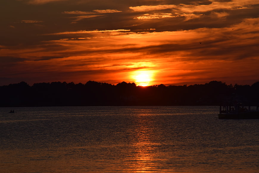 Vibrant Orange Sunset Over Calm Lake with Silhouette