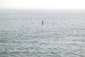 Lone paddleboarder on calm ocean water