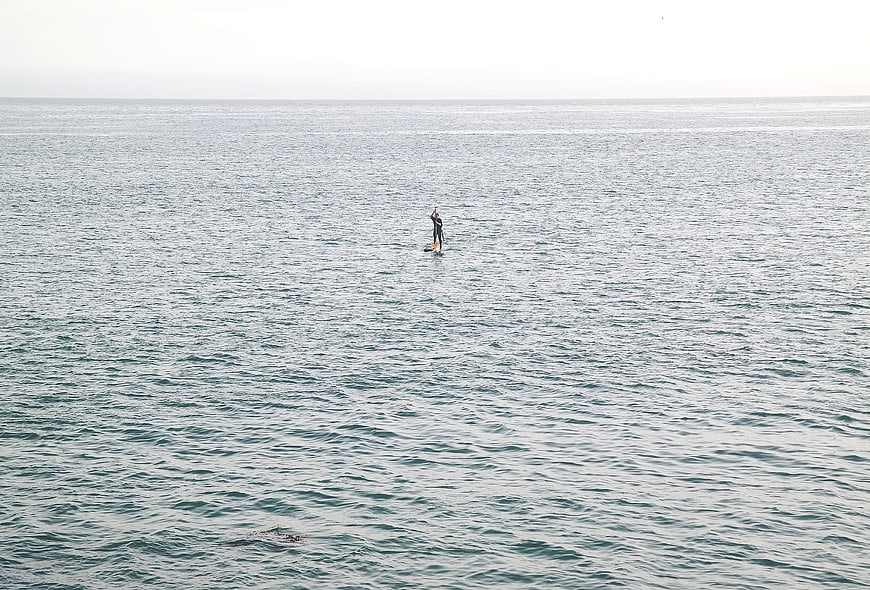 Lone paddleboarder on calm ocean water