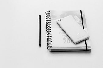 Minimalist black and white smartphone on notebook and pen