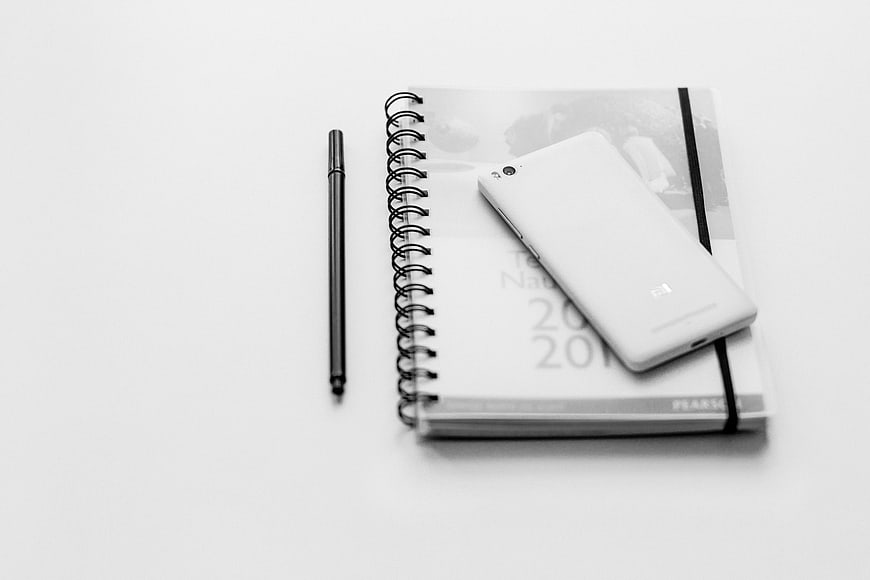Minimalist black and white smartphone on notebook and pen