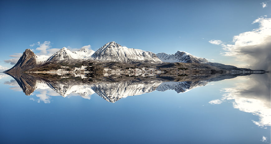 Snow-Capped Mountain Range Reflected in Calm Fjord Water