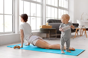 Mother doing yoga with toddler in bright living room