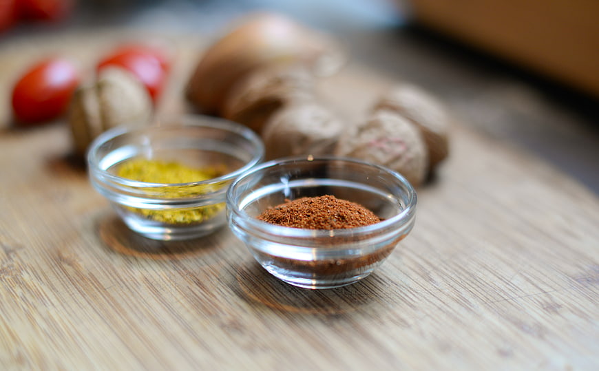 Ground spices in glass bowls on wooden table