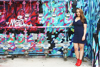 Woman in Navy Dress and Red Boots Against Colorful Graffiti Wall