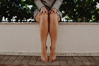 Barefoot Woman Sitting on Wall with Legs