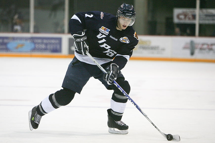 Ice hockey player skating with puck on rink