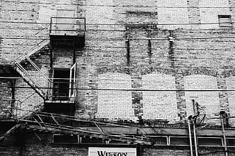 Black and white urban brick wall with fire escape
