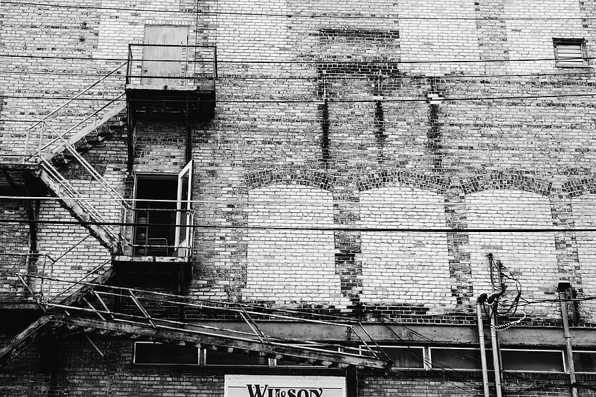Black and white urban brick wall with fire escape