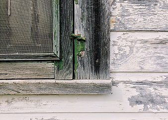 Weathered wooden window with peeling paint on rustic cabin exterior