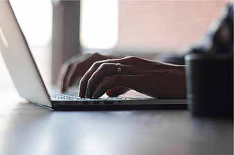 Close-up of hands typing on a laptop keyboard in an office