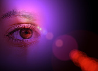 Close-up of a human eye with purple and red neon bokeh lighting